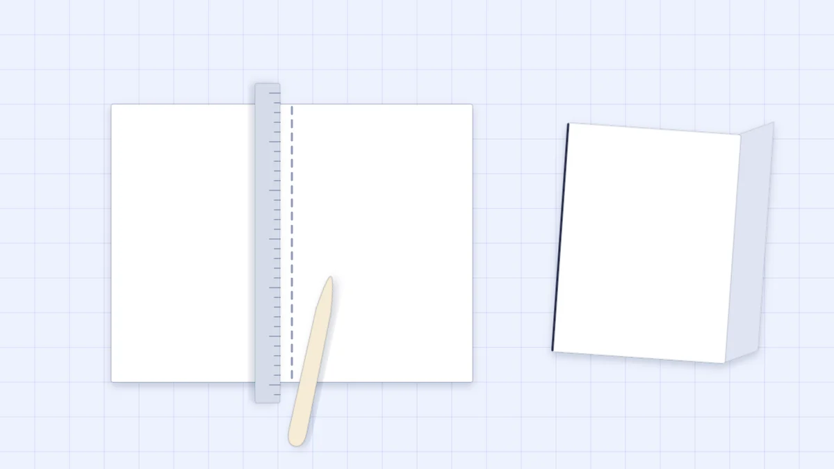 A sheet of cardstock scored along a ruler with a bone folder, next to a neatly folded card base